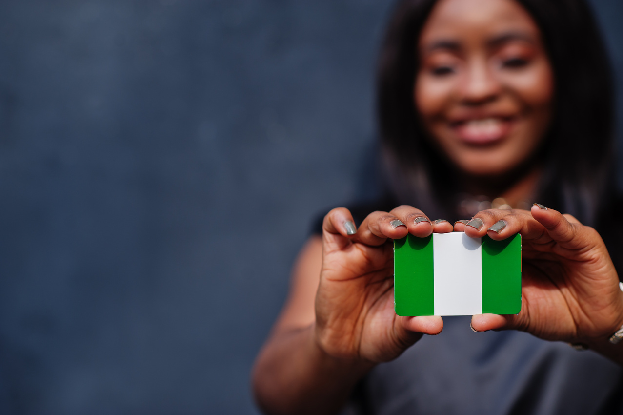 African woman hold small Nigeria flag in hands.